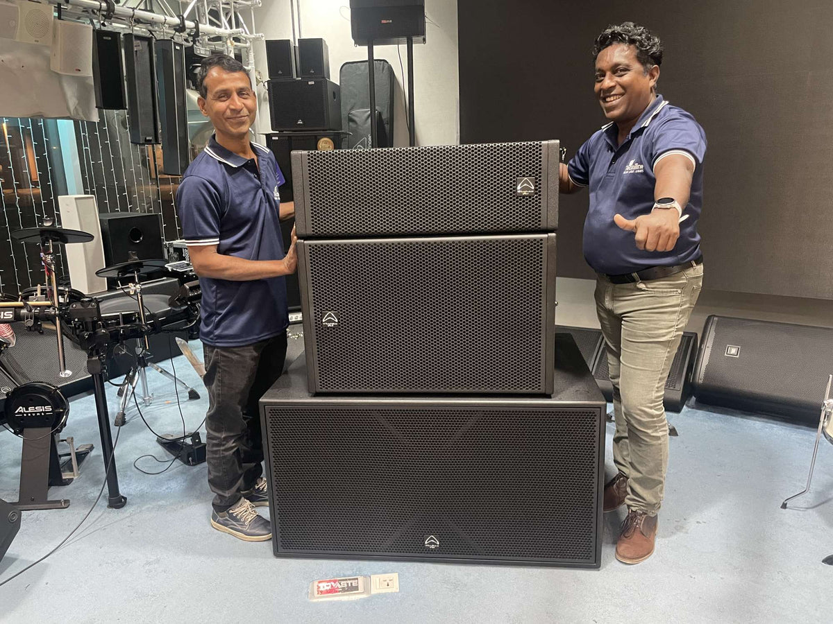 Two Techniline staff standing beside Wharfedale Pro line array subwoofers in the Dubai showroom